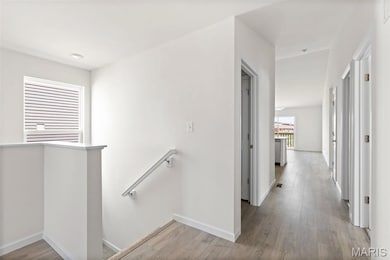 Corridor featuring an upstairs landing and wood finished floors