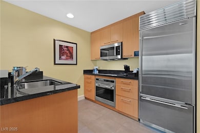 Kitchen with stainless steel appliances, dark stone counters, light tile patterned flooring, recessed lighting, and modern cabinets