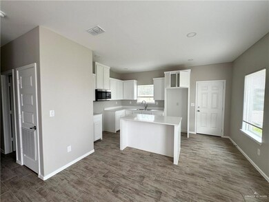 Kitchen featuring stainless steel microwave, a sink, healthy amount of natural light, and white cabinets