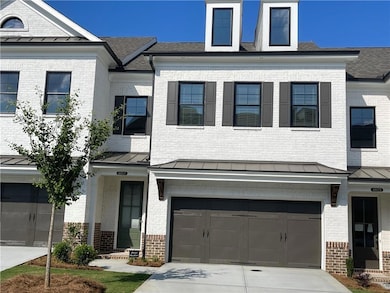 View of front facade with a standing seam roof, brick siding, a garage, and driveway