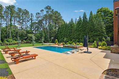 View of swimming pool featuring a patio, a pool with connected hot tub, a yard, and view of scattered trees