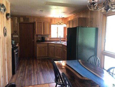 Kitchen featuring freestanding refrigerator, a sink, wooden walls, and plenty of natural light