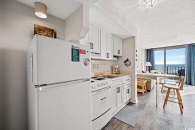 Kitchen with white appliances, a textured ceiling, white cabinetry, light wood finished floors, and a sink