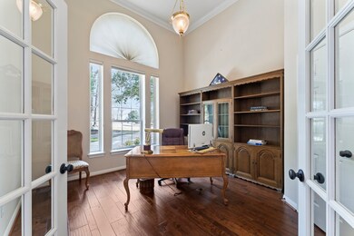 The dramatic office is a showcase, with its hardwood flooring and tall ceilings.  Features include double crown molding, a decorative chandelier nestled in a ceiling medallion, and a large window flanked by two side lights and an arched transom window above. There is also a closet for storage.