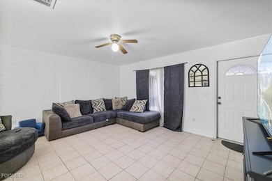 Living area featuring light tile patterned floors and ceiling fan