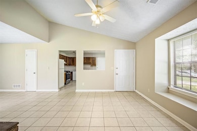 Unfurnished living room with lofted ceiling, healthy amount of natural light, a ceiling fan, and light tile patterned floors