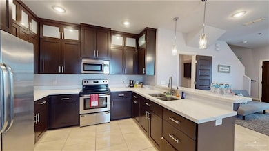 Kitchen featuring a sink, light countertops, a peninsula, appliances with stainless steel finishes, and visible vents