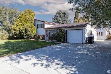 Tri-level home with a front yard, driveway, an attached garage, RV parking and workshop