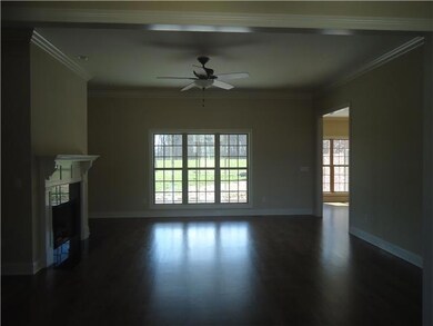 The living room is open to the foyer and features gleaming hardwood floors, fireplace, crown molding and triple windows overlooking the screened porch.