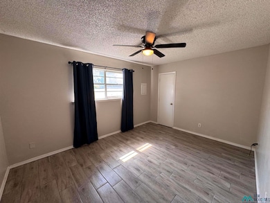 Empty room featuring a textured ceiling, light wood-style flooring, and ceiling fan