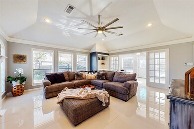 Spacious living room with recently replaced tile flooring, angle tray ceiling, crown molding, French doors leading to a gorgeous sun room for relaxation.