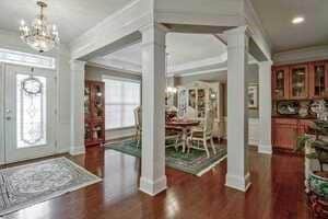 Entrance foyer featuring a chandelier, plenty of natural light, ornate columns, and ornamental molding