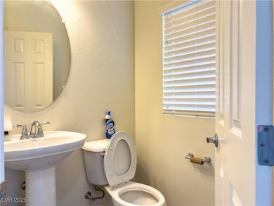 Bathroom featuring toilet, a sink, and a textured