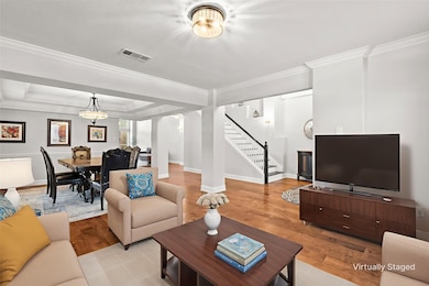 Living area with ornamental molding, stairway, wood finished floors, and a raised ceiling