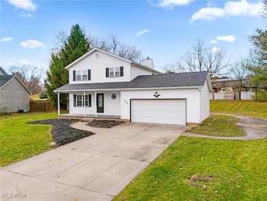 Traditional-style home featuring concrete driveway, an attached garage, a chimney, covered porch, and a shingled roof