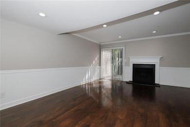Unfurnished living room featuring recessed lighting, dark wood finished floors, a fireplace with raised hearth, and crown molding