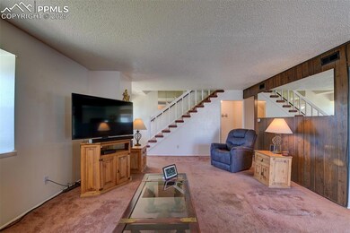 Unfurnished living room featuring stairs, carpet, a textured ceiling, and wood walls