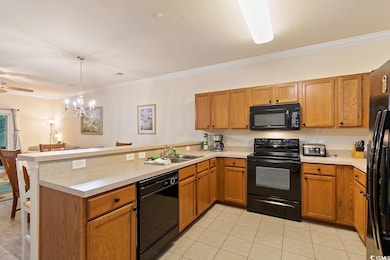 Kitchen featuring ornamental molding, black appliances, a peninsula, and brown cabinetry