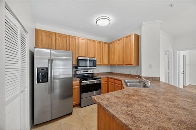 This bright, functional kitchen features warm maple cabinetry, ample counter space, and neutral tile flooring that complements the open layout. Stainless steel appliances, including a side-by-side refrigerator, smooth-top range, built-in microwave, and dishwasher, offer a modern touch and everyday convenience. A double stainless-steel sink and raised breakfast bar make meal prep and entertaining effortless.
