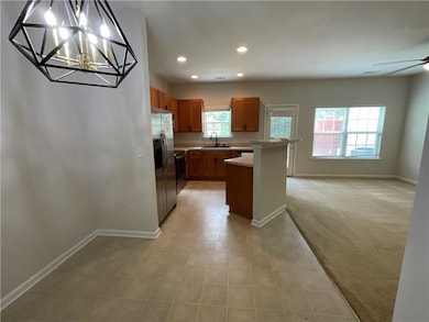 Kitchen featuring stainless steel fridge, baseboards, a sink, light countertops, and recessed lighting