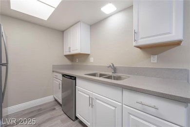 Kitchen with white cabinetry, light wood-type flooring, stainless steel appliances, and light stone countertops
