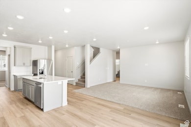 **DISCLAIMER - some exterior and interior options may vary**Kitchen featuring an island with sink, recessed lighting, gray cabinets, stainless steel fridge, and tasteful backsplash