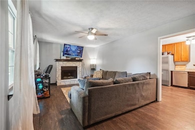 Living room featuring a stone fireplace, ceiling f