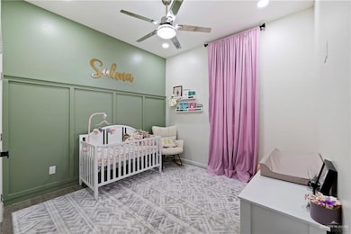 Bedroom featuring a nursery area, a decorative wall, a ceiling fan, and recessed lighting
