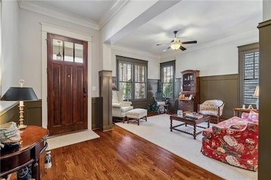 Entrance foyer featuring a wainscoted wall, wood finished floors, ceiling fan, and crown molding