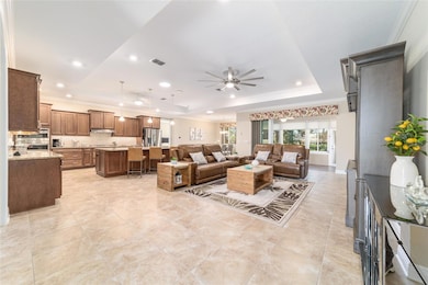 Open floor plan with tray ceiling, crown molding, custom window treatments, and modern fans.