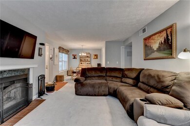 Living room featuring a chandelier, a fireplace, dark colored carpet, and a textured ceiling