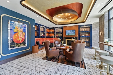 Sitting room featuring a tray ceiling, built in shelves, a glass covered fireplace, and recessed lighting