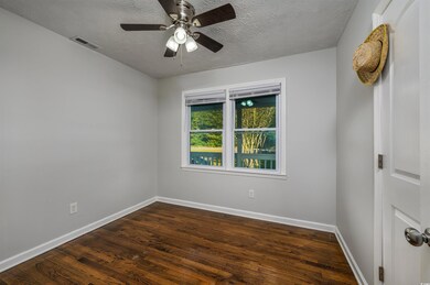 Unfurnished room with dark wood-type flooring, a t