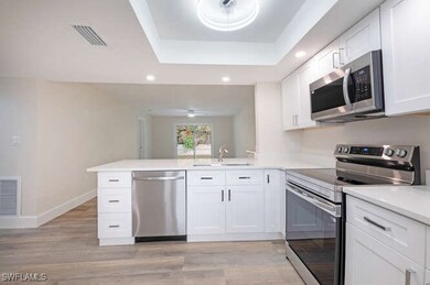 Kitchen with sink, white cabinetry, kitchen penins