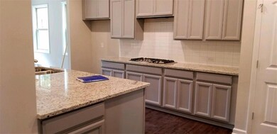 Kitchen with stainless steel gas stovetop, gray cabinets, and tasteful backsplash