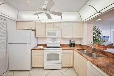 Kitchen with white appliances, light tile patterned flooring, dark stone countertops, recessed lighting, and ceiling fan