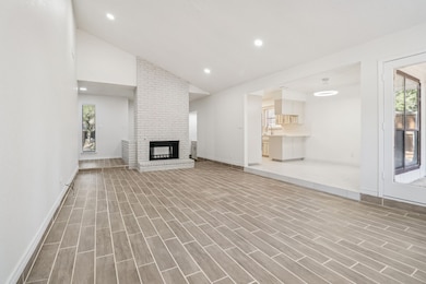 Unfurnished living room with recessed lighting, a fireplace, high vaulted ceiling, and wood finish floors