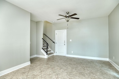 Empty room with ceiling fan, stairs, and light tile patterned floors