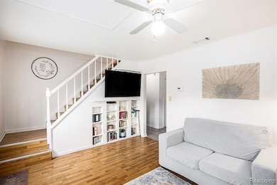 Living area featuring wood finished floors, ceiling fan, and stairs