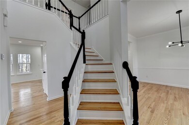 Stairway with crown molding, a chandelier, wood fi