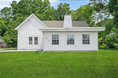 Front of house featuring a yard, a shingled roof, and a chimney