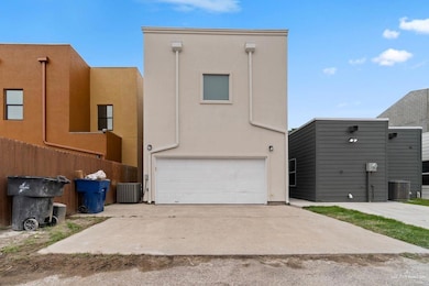 Back of house with stucco siding, a garage, and driveway