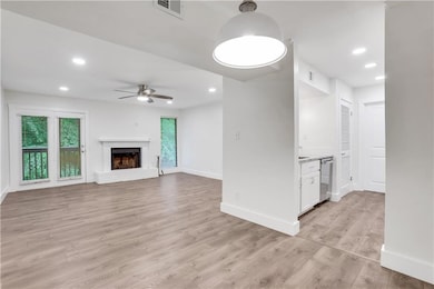 Unfurnished living room featuring a ceiling fan, light wood-style floors, baseboards, recessed lighting, and a fireplace
