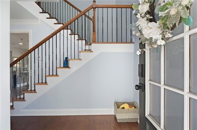 Stairway with wood finished floors, baseboards, and ornamental molding
