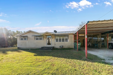 View of front of property with a front yard, a carport, and a metal roof