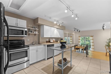 Kitchen featuring white cabinets, stainless steel appliances, light tile patterned floors, and open shelves