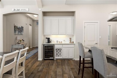 Bar featuring white cabinetry, beverage cooler, backsplash, and light stone countertops