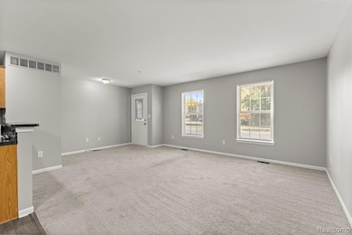 Unfurnished living room featuring carpet floors and baseboards
