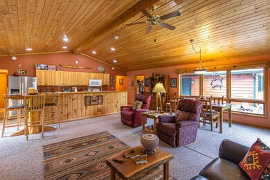 Carpeted living room featuring ceiling fan, vaulte