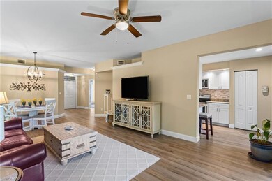 Living room with light wood finished floors, a ceiling fan, and a chandelier